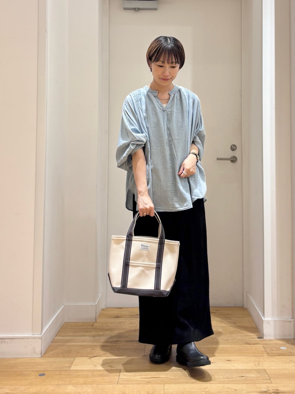 ブルー系のシャツ/ブラウス、ブラック系のスカート、ホワイト系のトートバッグを着用したレディースの夏コーディネートの1枚目の写真