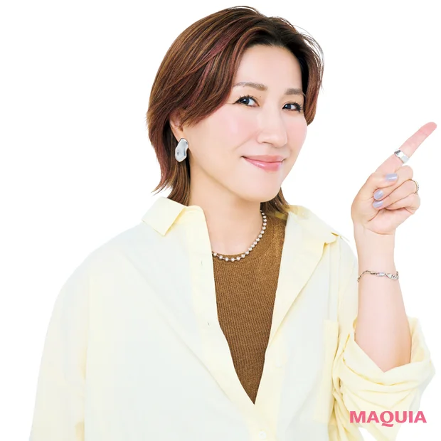 左手の人差し指を斜め上に立て、正面をむいている長井かおりさん