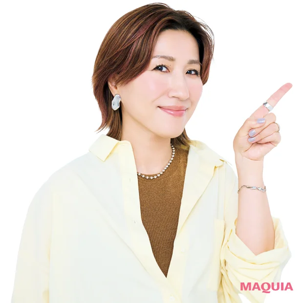 左手の人差し指を斜め上に立て、正面をむいている長井かおりさん