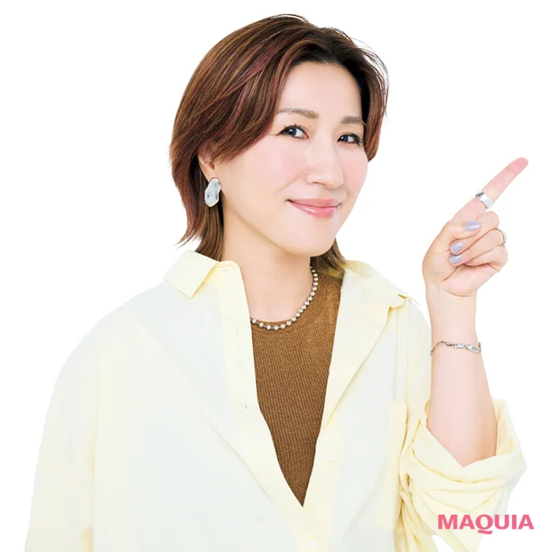 左手の人差し指を斜め上に立て、正面をむいている長井かおりさん